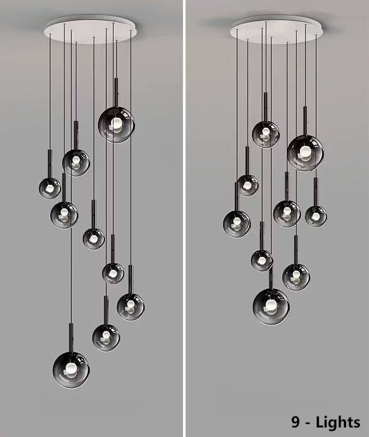 A unique set of nine gradient-colored glass pendant lights, suitable for high ceilings, features black gradient spherical lampshades of varying sizes and designs, including spiral and random arrangements, ideal for stairwells, foyers, and entryways.