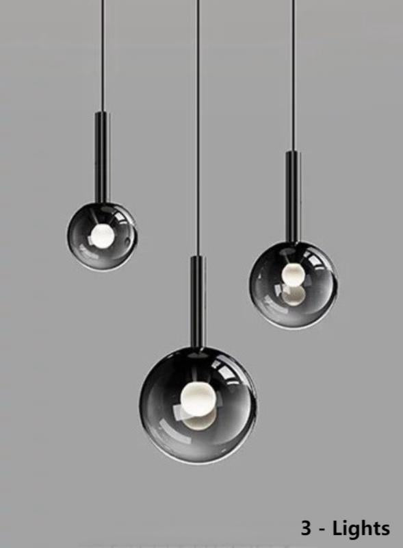 Three luxurious pendant lights with gradient-colored glass shades, suitable for dining tables and entryways. The black gradient spherical lampshades come in varying sizes, ideal for relatively smaller spaces.