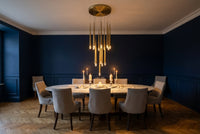 Thumbnail for Dining room with a round table and chairs under a modern chandelier.
