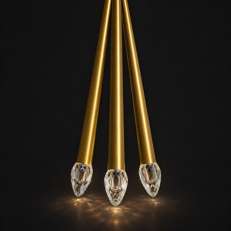Three gold pendant lights with crystal-like ends on a black background