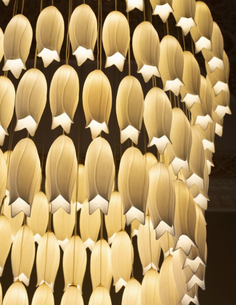 Handcrafted ceramic flower chandelier with hummingbird accents transforming staircase into botanical focal point for foyer