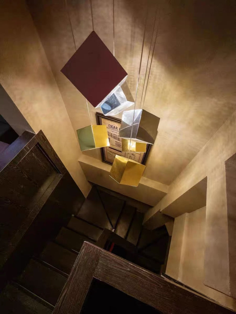 This pendant light features a gold-plated chrome alloy finish and a glass shade in the shape of an ice cube, making it suitable for small stairwells.