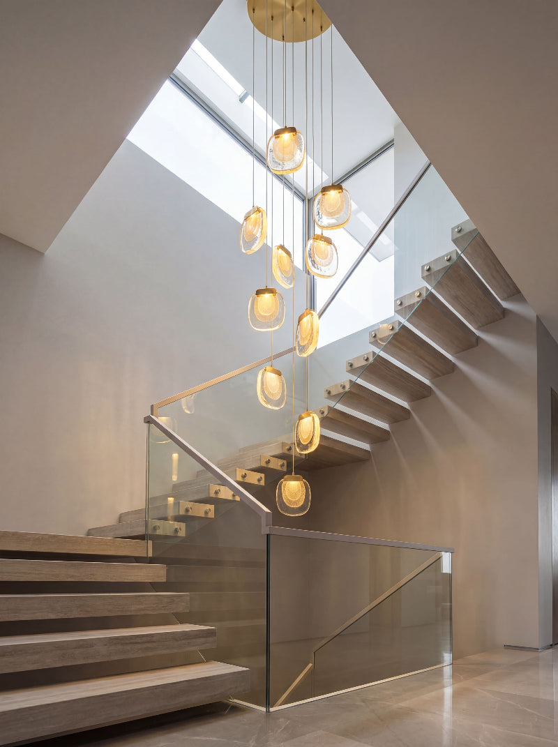 Luxury gold cascade chandelier with cascading crystal strands creating dramatic waterfall lighting in two-story foyer entryway