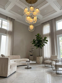 Thumbnail for Modern golden cascade crystal pendant light with layered waterfall design illuminating contemporary living room high ceiling space