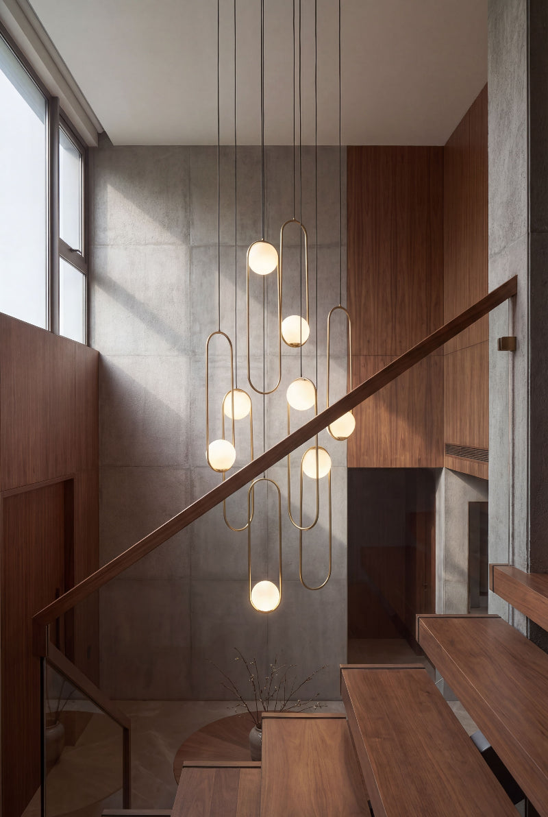 Designer glass globe staircase chandelier with mixed gold and black finish creating artistic lighting installation in modern interior