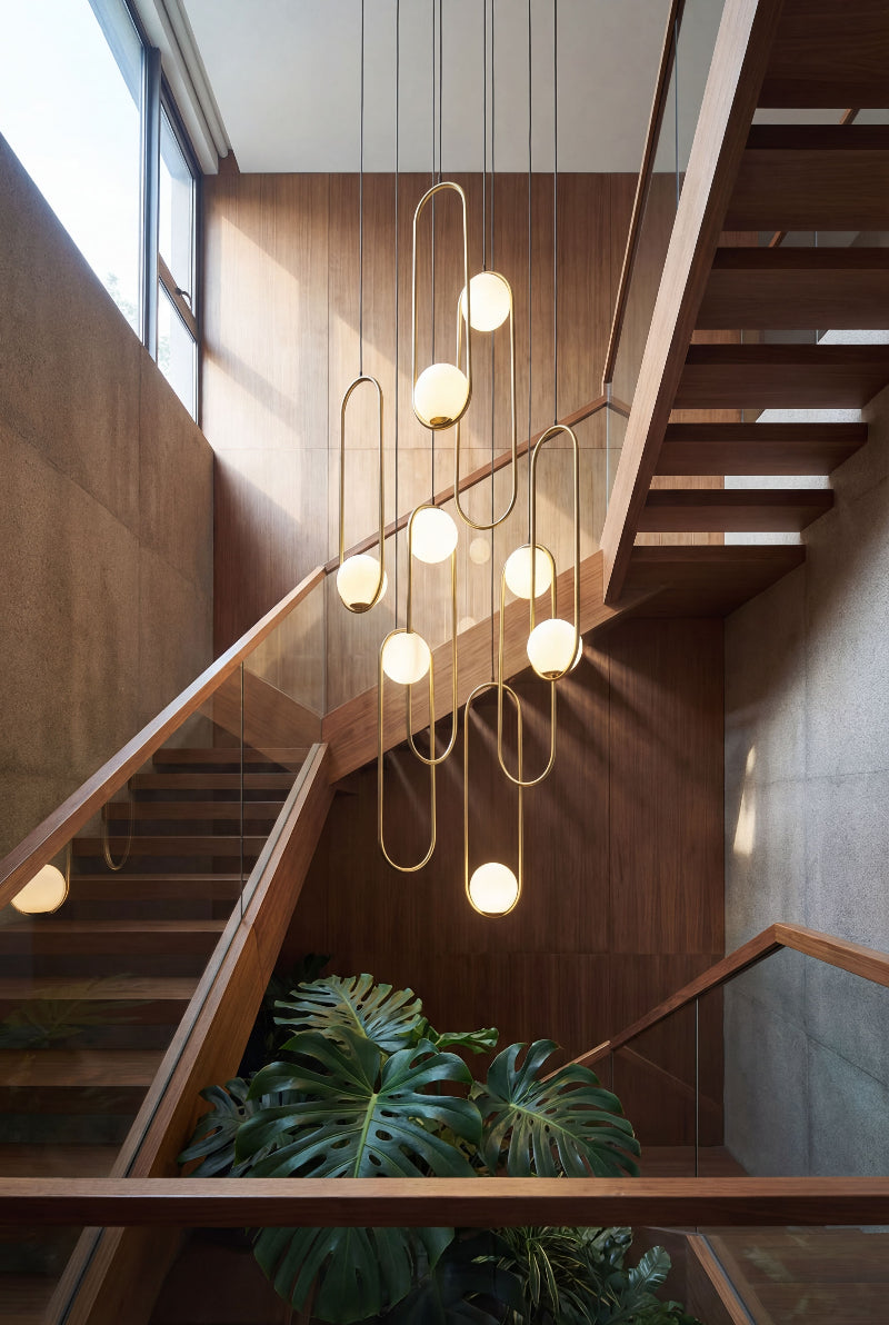 Contemporary gold glass globe staircase chandelier with multiple pendants creating elegant cascading lighting in modern two-story foyer