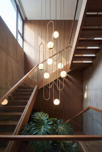 Thumbnail for Contemporary gold glass globe staircase chandelier with multiple pendants creating elegant cascading lighting in modern two-story foyer