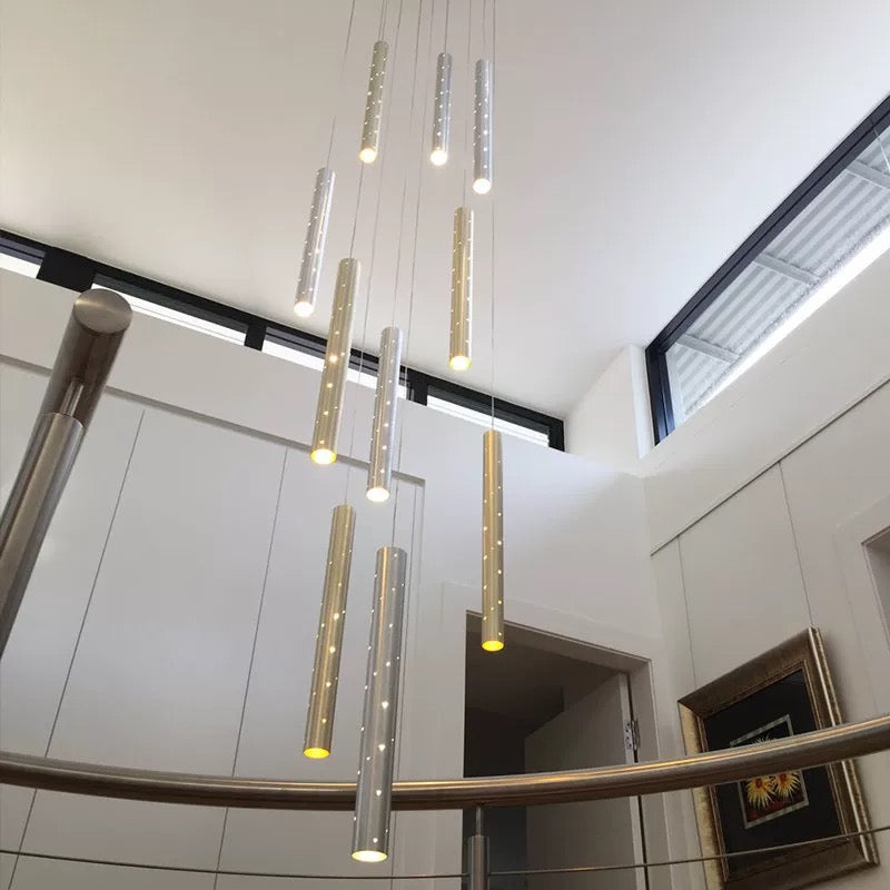 This modern, minimalist linear cylindrical pendant light is suitable for staircases.  Featuring a silver "shooting star" design and perforated light tubes, it provides illumination for the stairs.