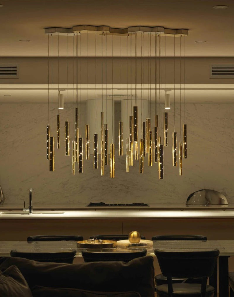 Modern linear cylinder chandelier in dining room, gold meteor shower design with perforated tubes for kitchen island