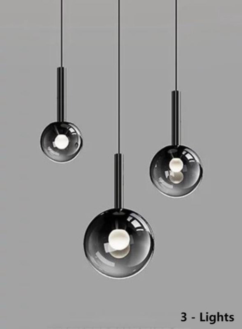 Three luxurious pendant lights with gradient-colored glass shades, suitable for dining tables and entryways. The black gradient spherical lampshades come in varying sizes, ideal for relatively smaller spaces.