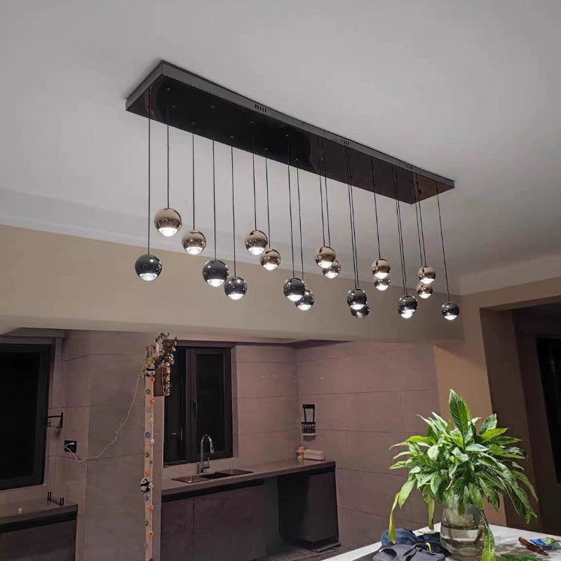 This handcrafted cognac-colored glass pendant light, featuring truffle-shaped gold sphere accents, is perfect for use above a kitchen island or dining table.