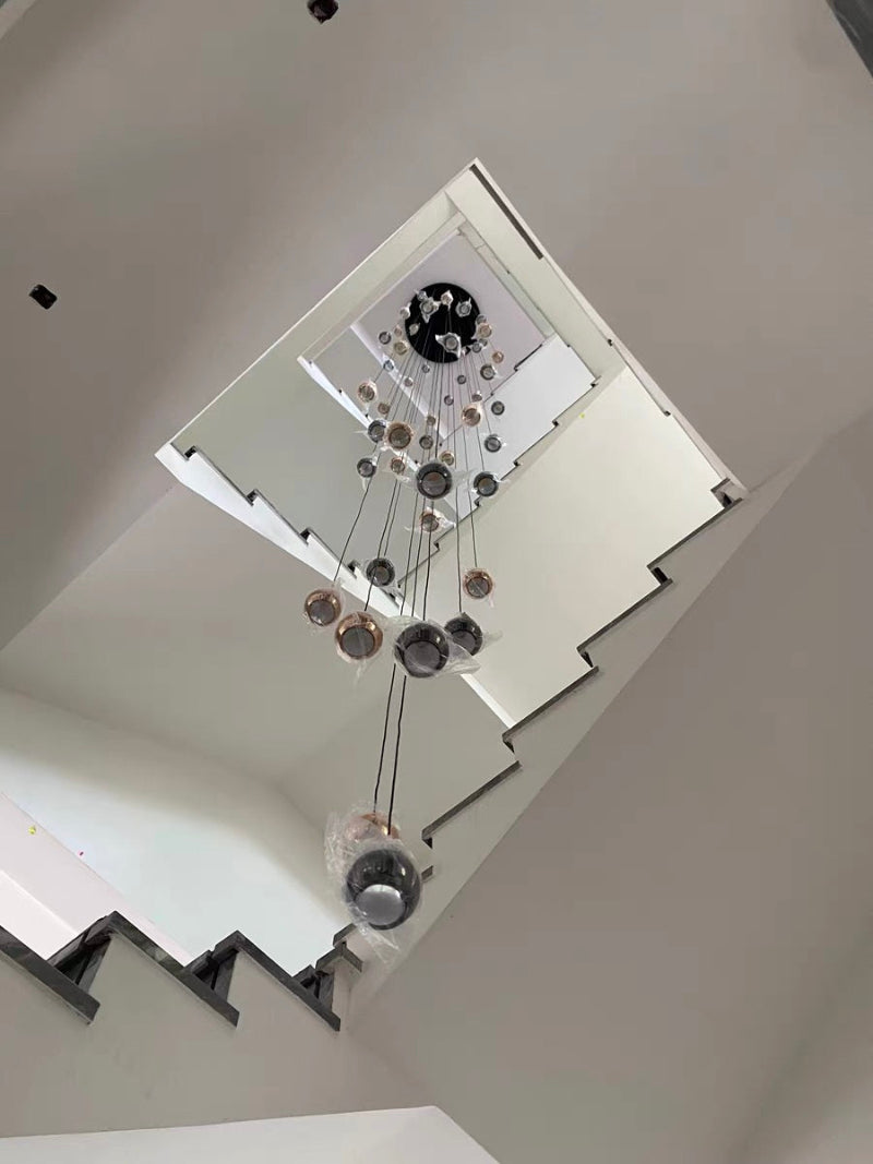 An elegant staircase chandelier, featuring cognac-colored glass and bronze truffle-shaped design with a gold finish, creates a warm glow in the two-story foyer and staircase entrance.