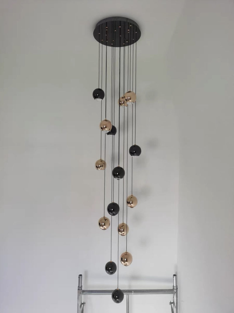 Modern pendant light with multiple spherical bulbs on a white wall background