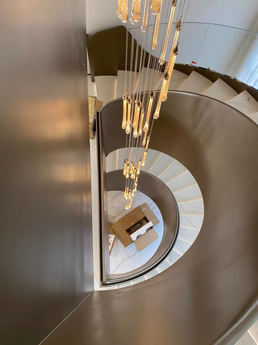 The warm, golden "Angel's Tears" crystal chandelier, with its cascading teardrop design, creates an elegant atmosphere for the staircase.