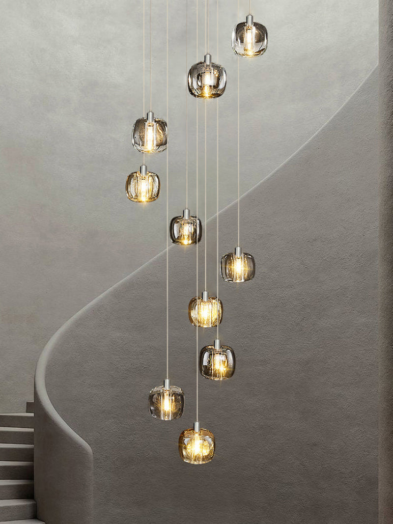 A modern staircase square crystal chandelier with brass fittings hanging in a luxurious interior space, highlighting its elegant design and contemporary style.