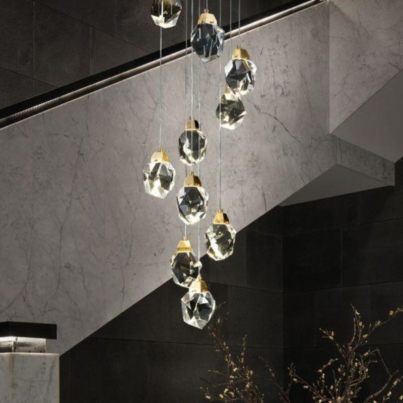 Modern geometric hanging light with irregular cut crystal chandelier in a luxurious interior setting, featuring a spiral arrangement of crystal pendants in a warm brass finish.