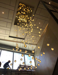 Thumbnail for bubble crystal chandelier, featuring warm, dimmable LED, is suitable for spaces such as stairwells, foyers. The image shows the chandelier being installed by an electrician on-site.