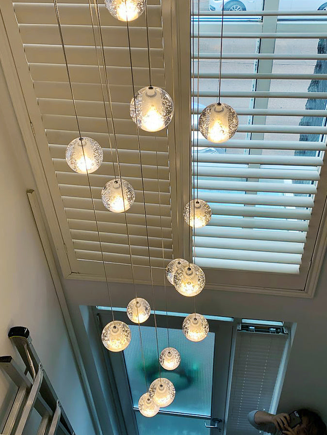 Modern chrome-plated bubble crystal chandelier with dimmable LED suspended spheres, suitable for stairwells, foyers, entryways, or double-height ceilings.  The image shows the installation in an entryway.