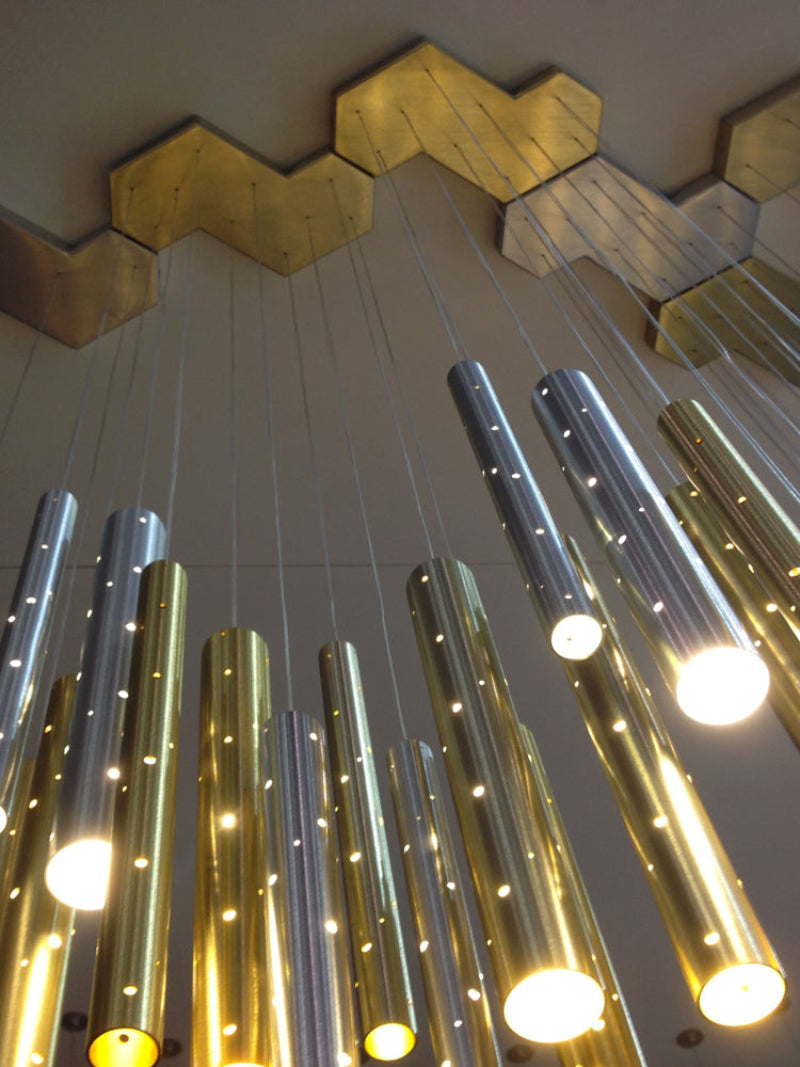 Chandelier with gold and silver cylindrical lights on a ceiling
