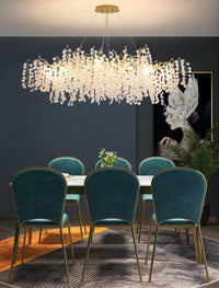 Thumbnail for Modern linear tree branch chandelier with glass-like leaves creating artistic botanical fixture over dining table providing warm white light