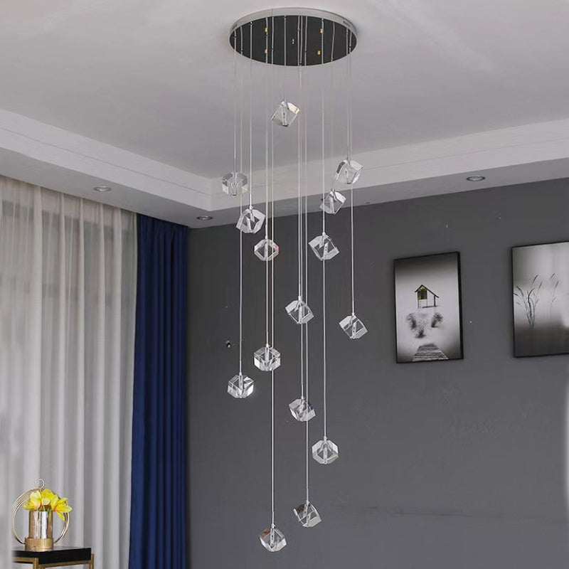 Modern chandelier with crystal elements hanging from the ceiling in a room with gray walls and a window.