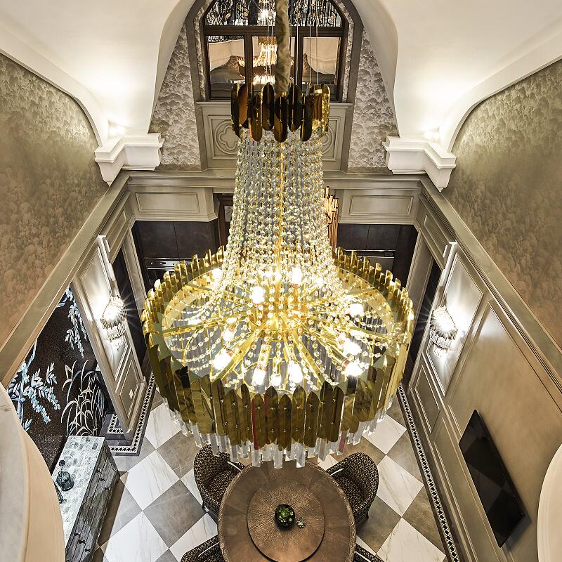 A modern gold crystal chandelier with a starburst silhouette, hanging in a luxurious interior setting, providing ambient lighting.