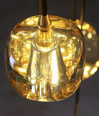 Thumbnail for An amber-colored, square crystal chandelier with a spiral design, suitable for high-ceilinged spaces such as stairwells, foyers, and entryways.