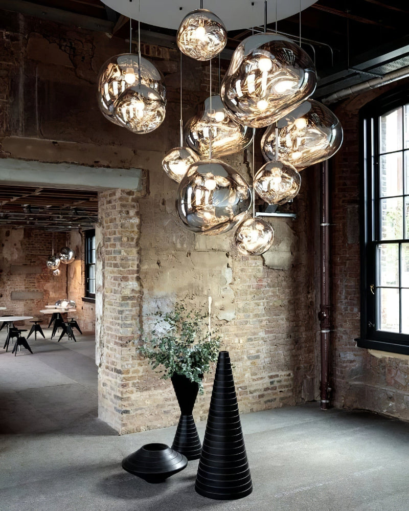 Modern chandelier hanging in a stylish room with brick walls and industrial decor.