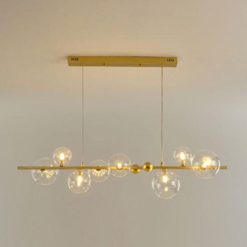 Gold pendant light fixture with multiple glass bulbs on a plain background