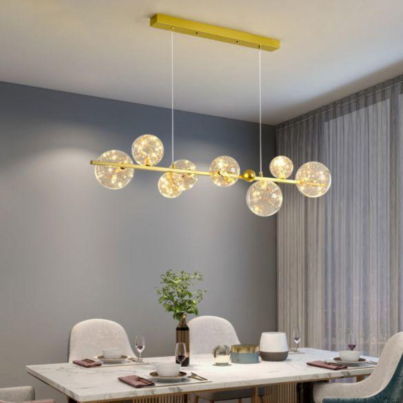 Modern chandelier hanging above a dining table in a room with gray walls and a curtain.