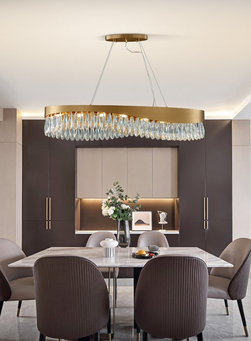 Oval crystal chandelier in dining room setting, gold frame with K9 crystals, modern ambient lighting