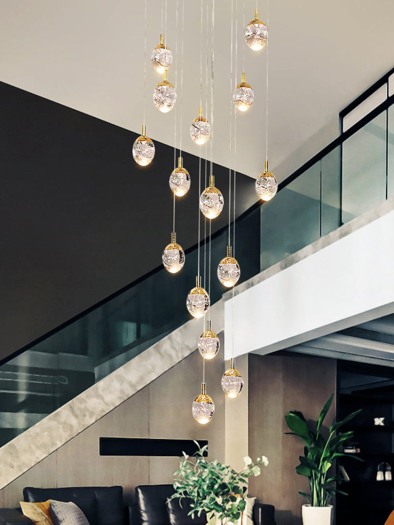 Modern chandelier hanging in a stylish interior setting with a staircase and plants.