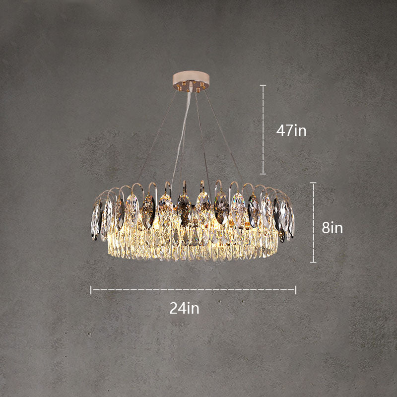 A modern gold crystal chandelier hanging in a living room setting, with a round glass table and beige sofa below.