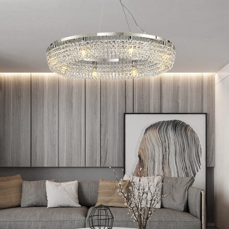 Modern crystal ring chandelier with LED bulbs, hanging over a living room setting, showcasing a contemporary style with a silver finish.
