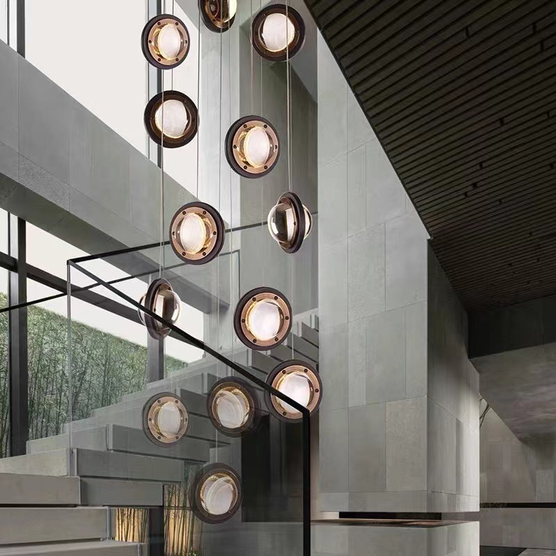 Modern crystal chandelier with a spiral design, featuring clear glass bubbles and gold-colored metal parts, installed in a staircase setting.
